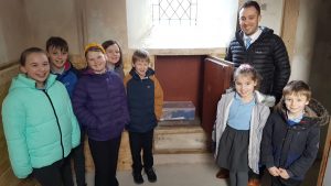Mr Aron Jones, deputy head teacher at Ysgol Bro Gwydir with members of the school council, placing their time capsule box at St Grwst Church.